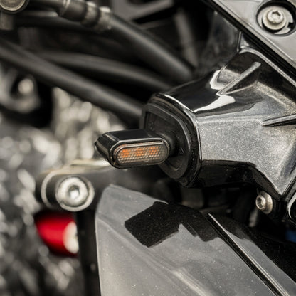 Mini intermitente LED ahumado encendido en ámbar montado en una Kawasaki Z900