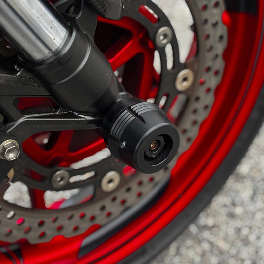 Protector de eje delantero montado en el centro de la rueda de una Kawasaki Z900 con llanta roja