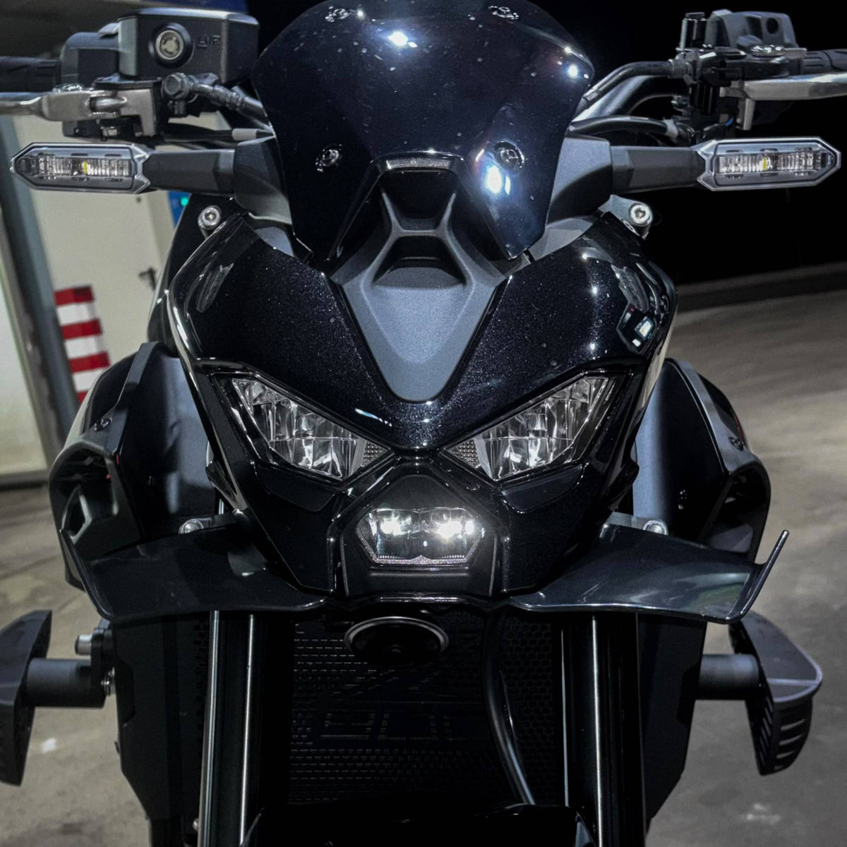 Frontal de una Kawasaki Z900 2025 negra con el alerón delantero deportivo montado